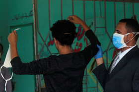 مراقب با ماسک دانش آموز مصری را بررسی می کند